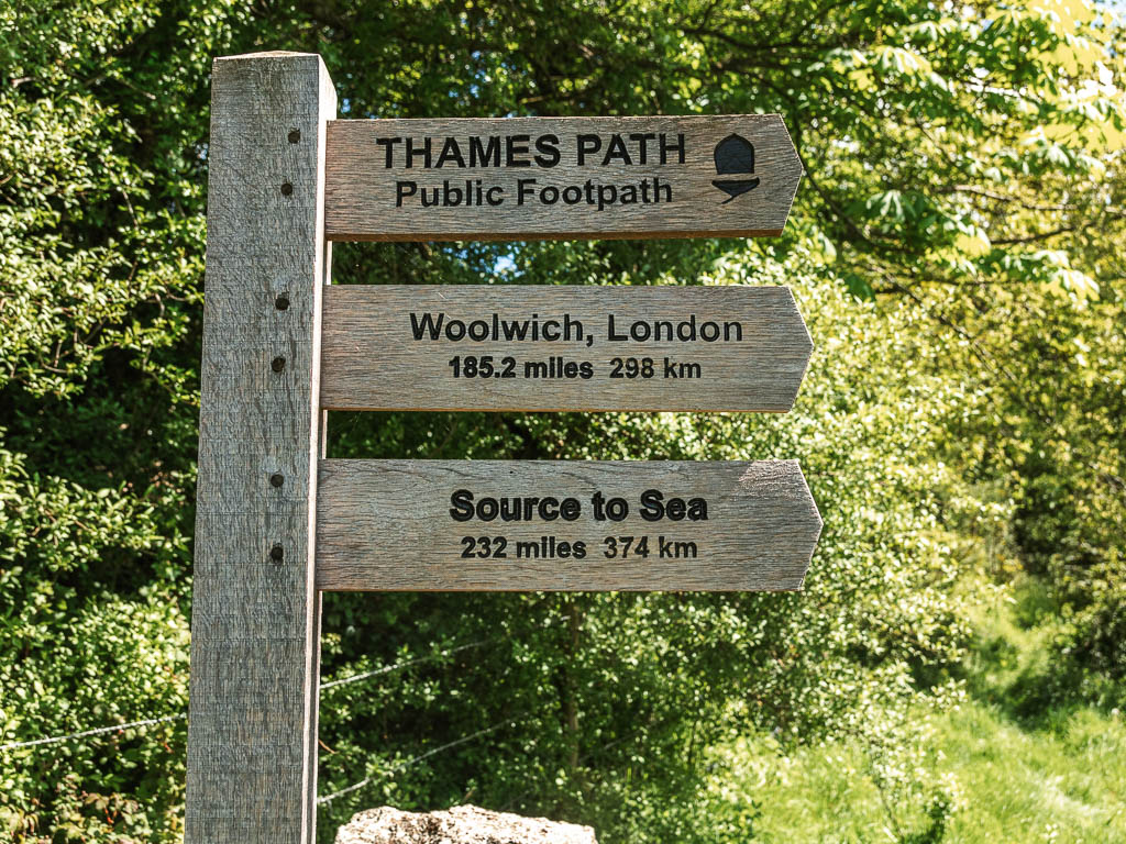 A wooden trail sign post pointing right for the Thames Path from the source to sea 232 miles.