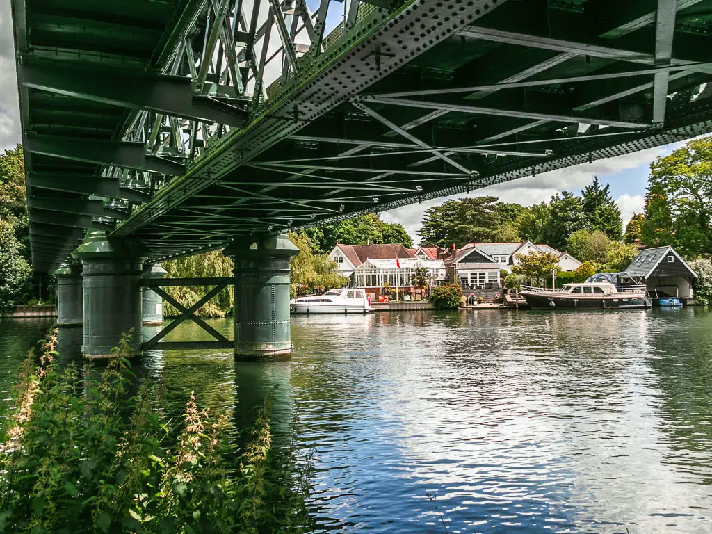 Looking under a metal bridge over the river, to some houses on the other side, partway through the walk from Marlow to Maidenhead.