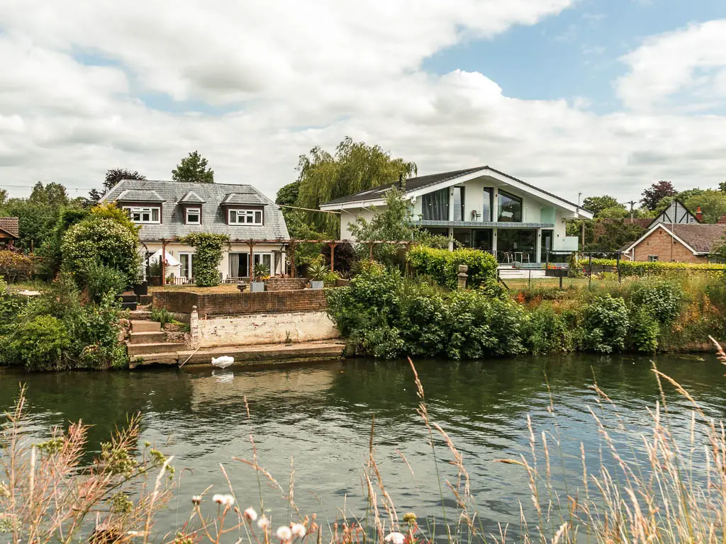 Looking across the river to the other side with nice houses, partially hidden by bushes on the walk from Windsor to Staines.