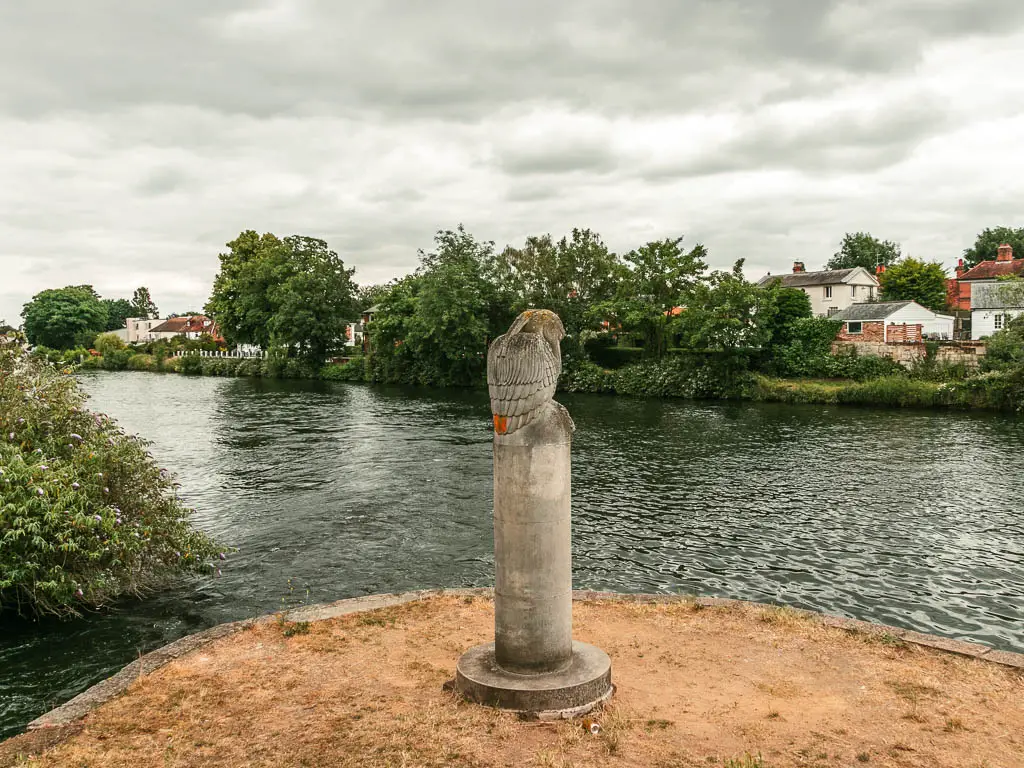 A stone owl statue next to the river.