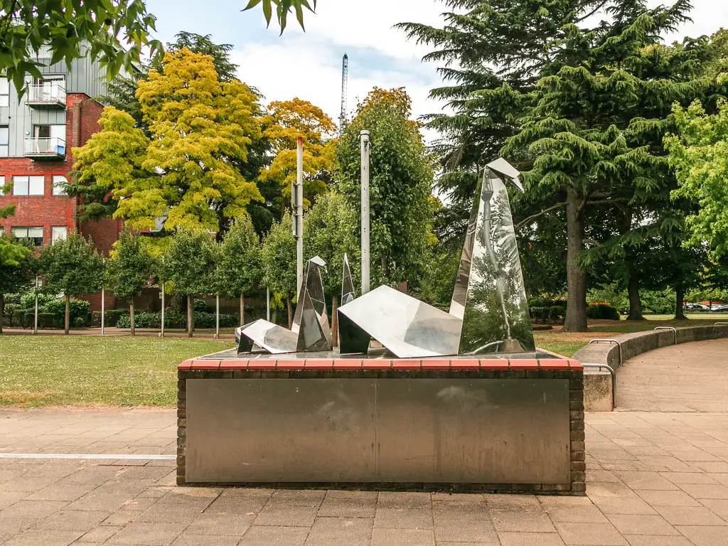 A mirrored swan sculpture on a platform.