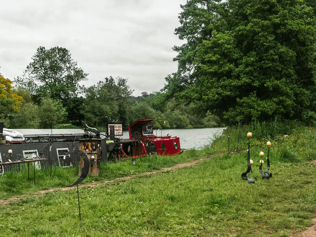 A grass field with the river to the left and a barge moored to the side.
