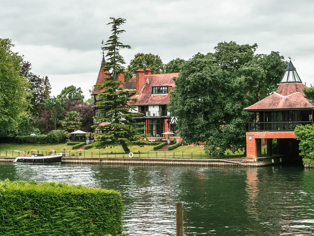 Looking across the river to a big house on the other side with a neatly cut lawn inferno and big trees, at the start of the walk from Maidenhead to Windsor.