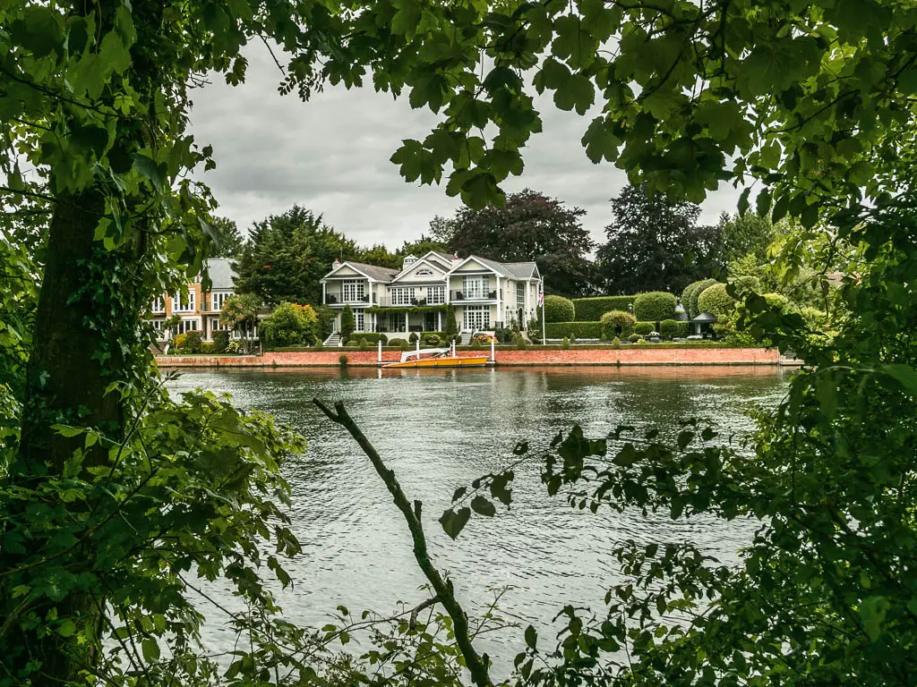 Looking through a gap in the trees to the river and big white coloured house on the other side, on the walk between Maidenhead and Windsor.