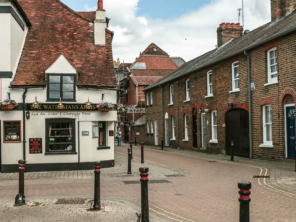 Looking along a road through the houses, and a white walled pub on the left corner.