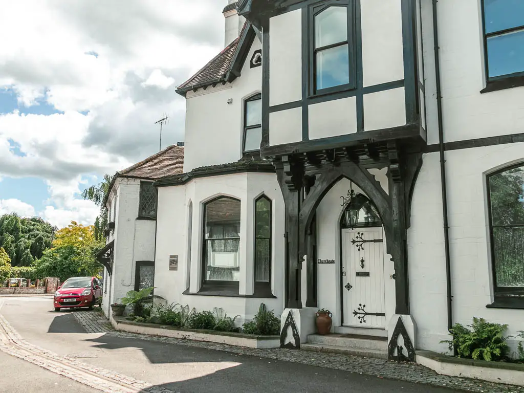 A big white walked house with black details, next to the road.