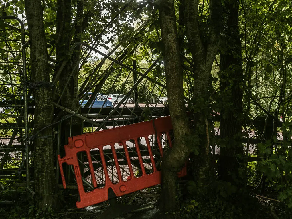 Three fences in the trees, blocking the route to the road on the other side.