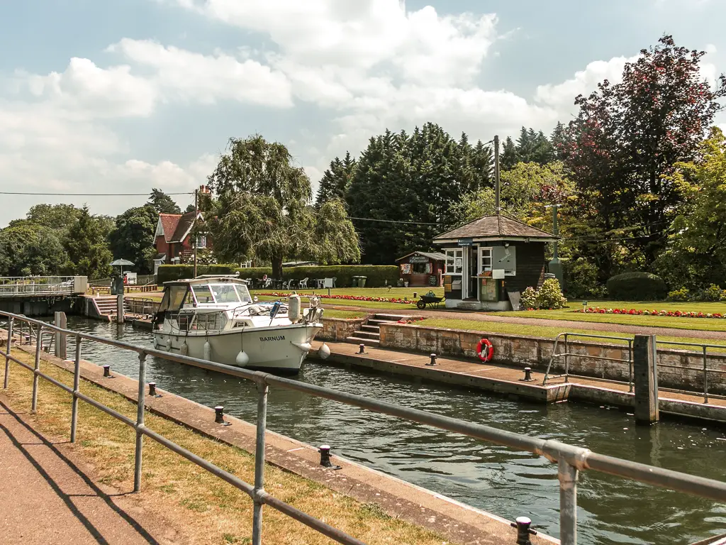 Looking over the metal railing to the lock with white boat inside the lock.