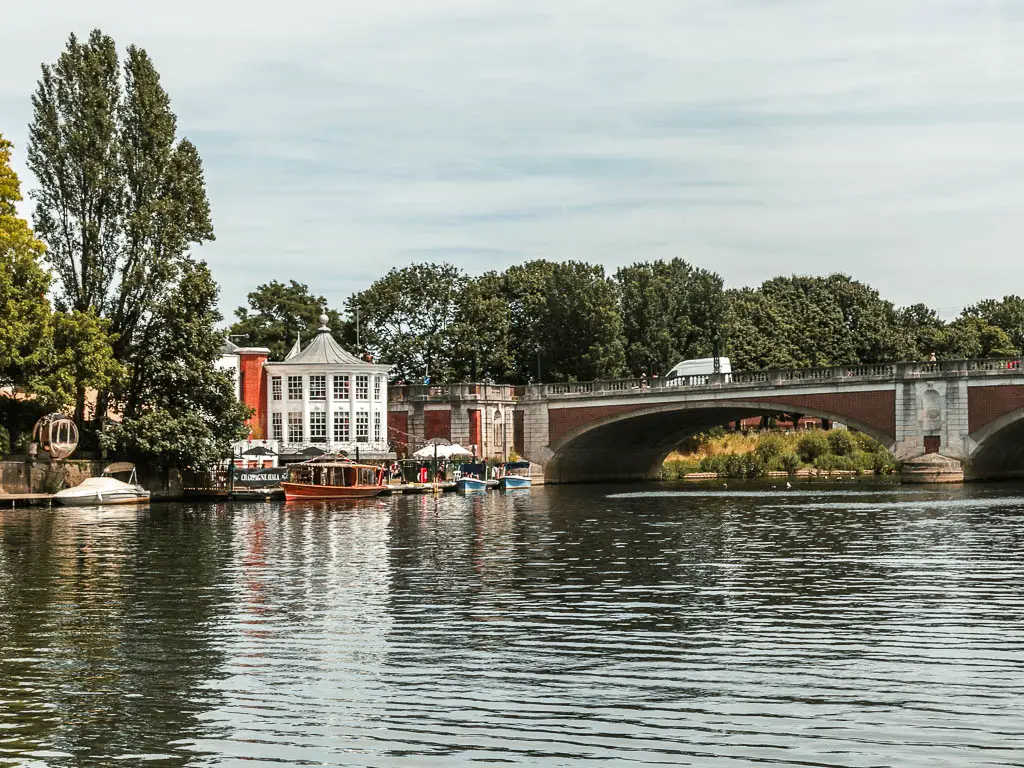 Looking across the river with ripples, with a big bridge, at the end of the walk from Shepperton to Hampton court. There are buildings on the other side of the river, and some trees.