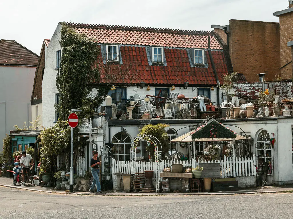 A shop front with lots of cute and quaint garden ornaments and furniture outside.