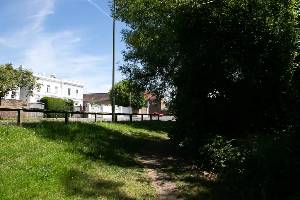 A grass verge leading up to the road with white walled hoses on the other side.