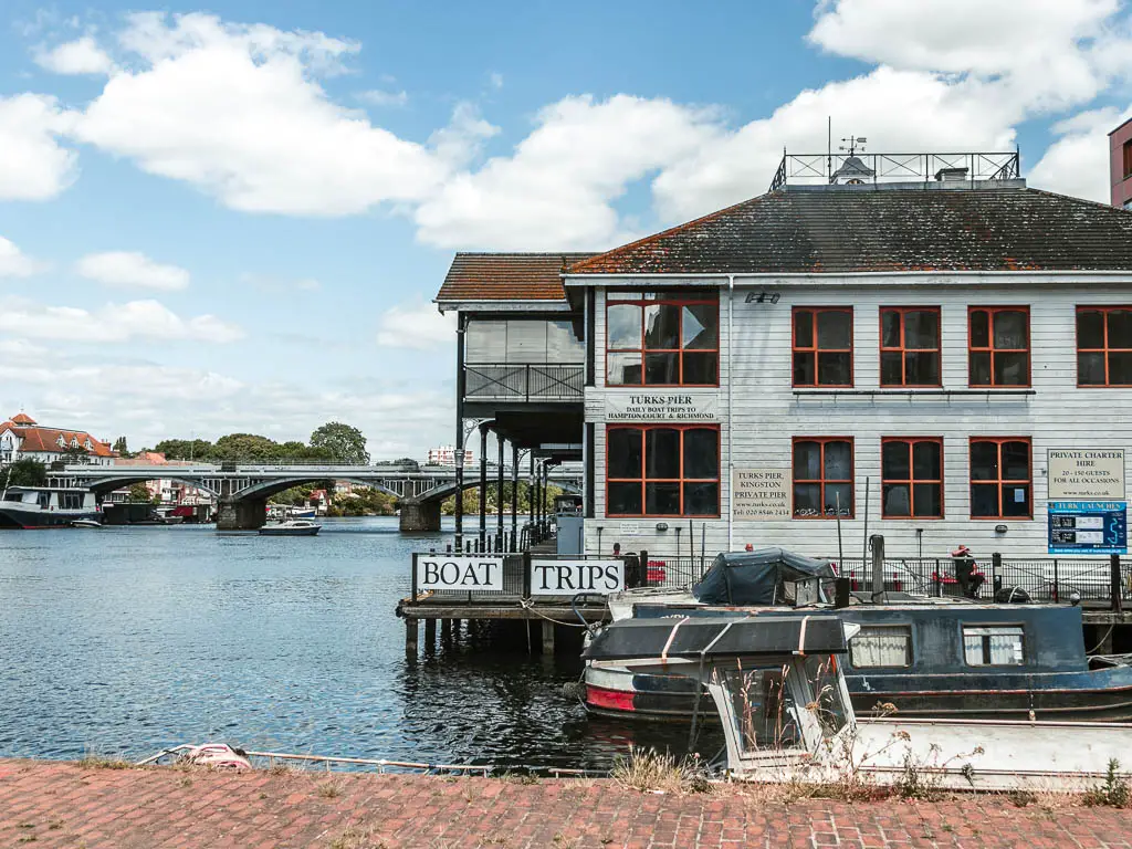 A white timber building jutting out over the river, with a sign saying 'boat trips'.