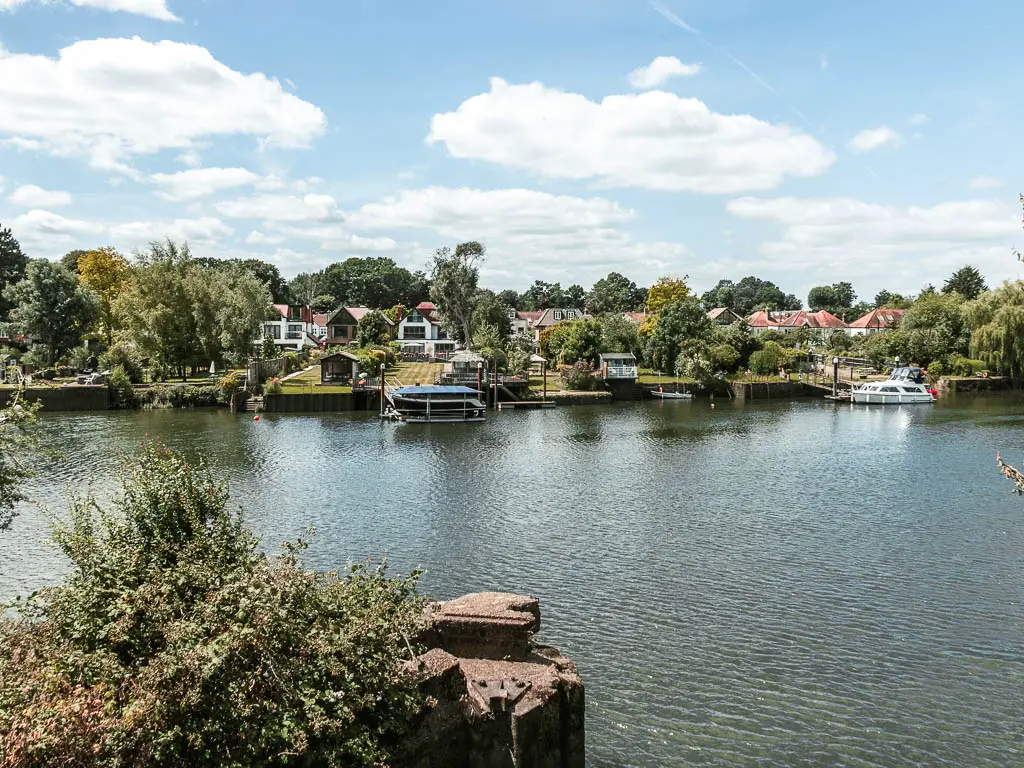 Looking down and across the river to small houses with green front lawns and trees on the other side.