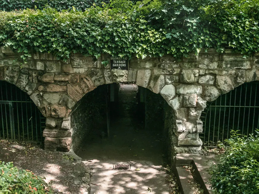 A stone archway leading to a tunnel, with a path running through it.