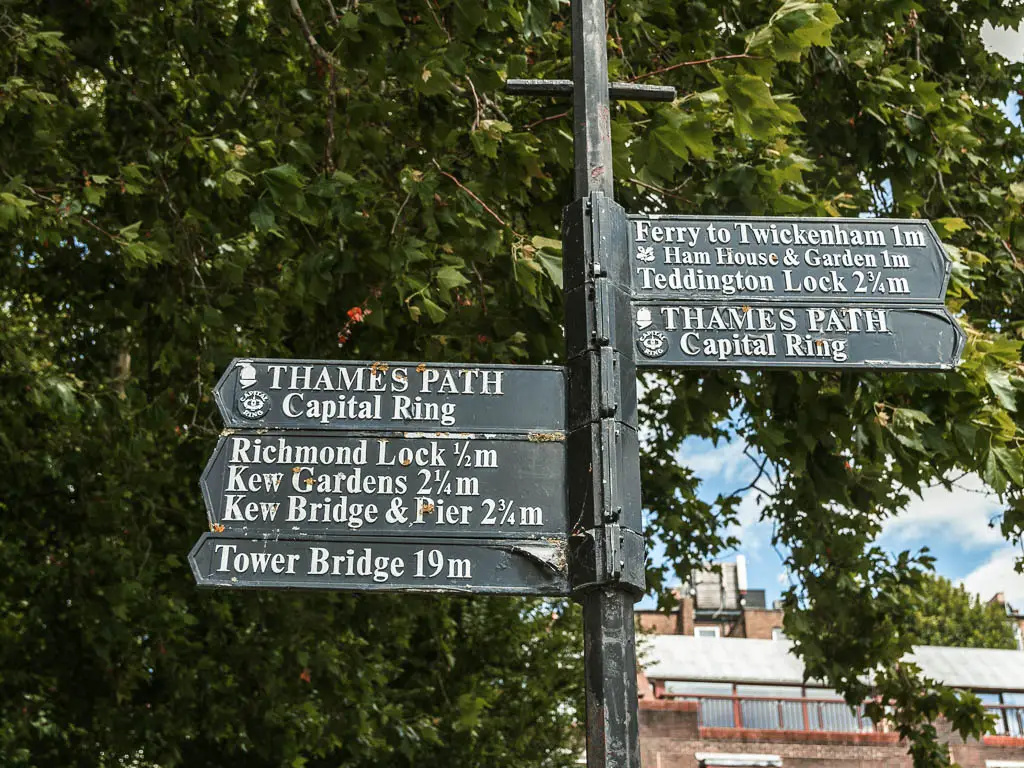 A black signpost pointing left and right for the Thames Path.