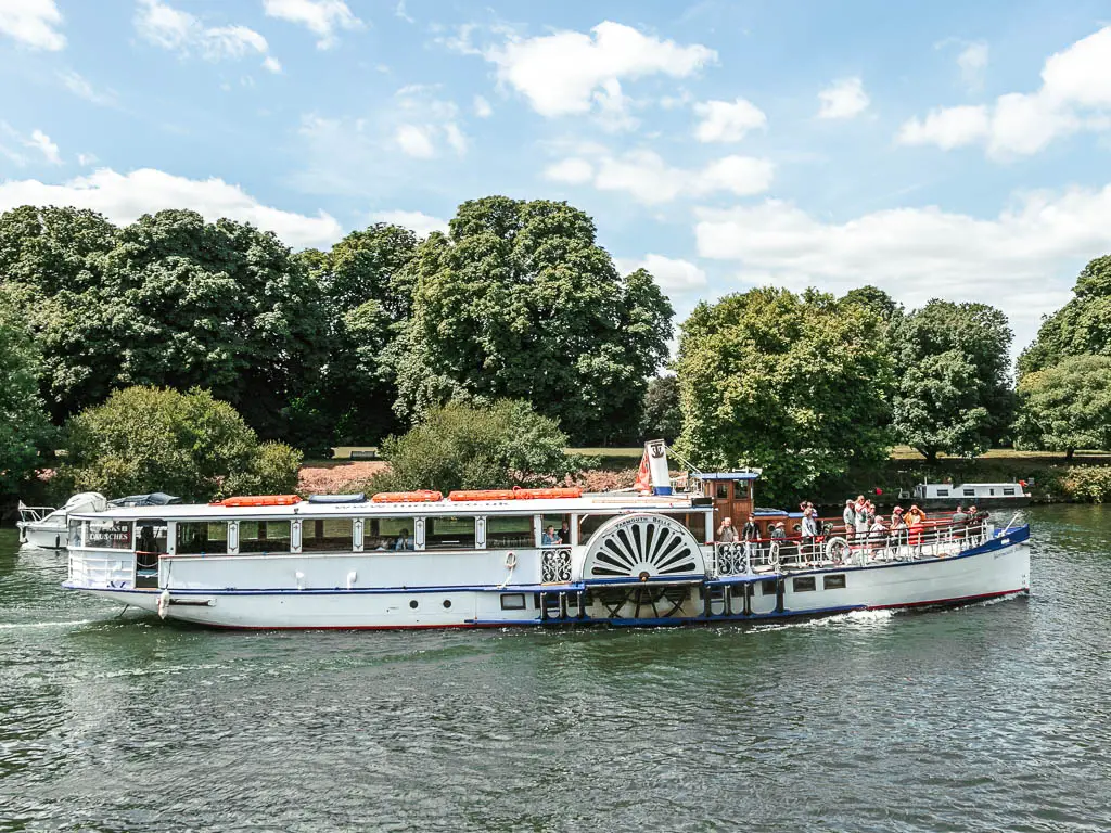 A big white tourist boat on the river, with trees on the other side in Hampton court, at the start of the walk towards Putney.