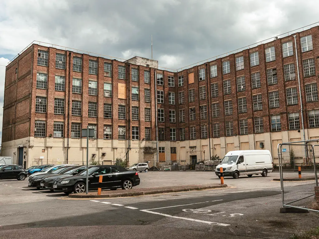 A large derelict factory building with car park in the middle, near the end of the Tower Bridge Thames Barrier walk. 