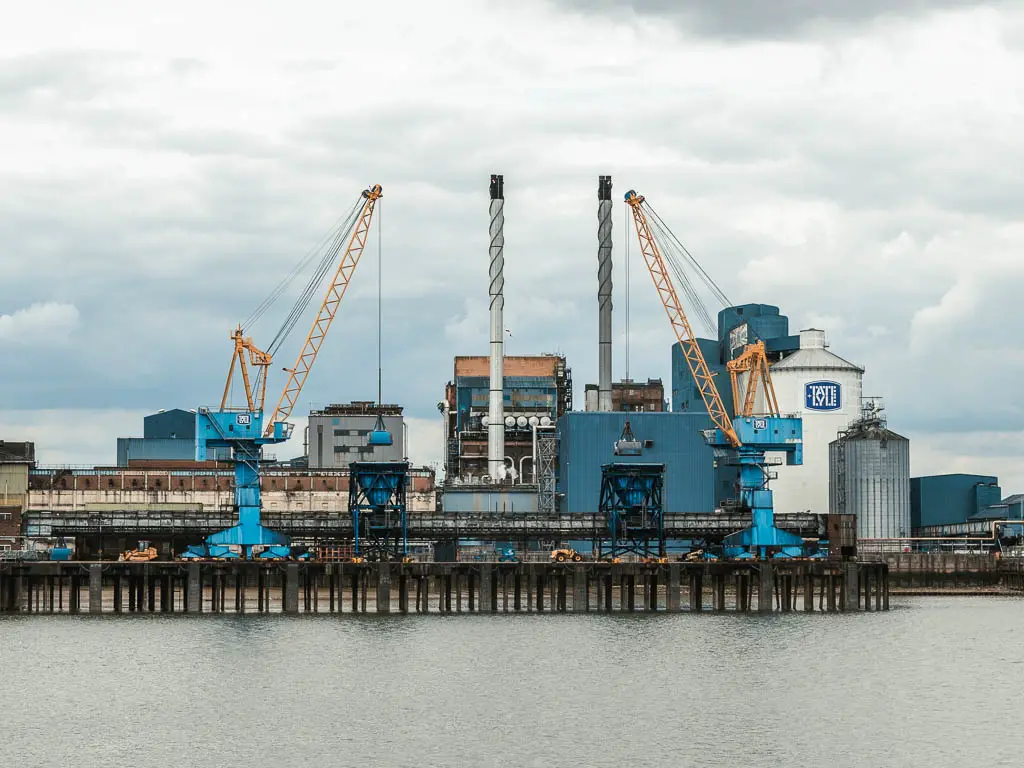 Looking across the river to an industrial site with machinery painted blue, when walk from Tower Bridge to the Thames Barrier.