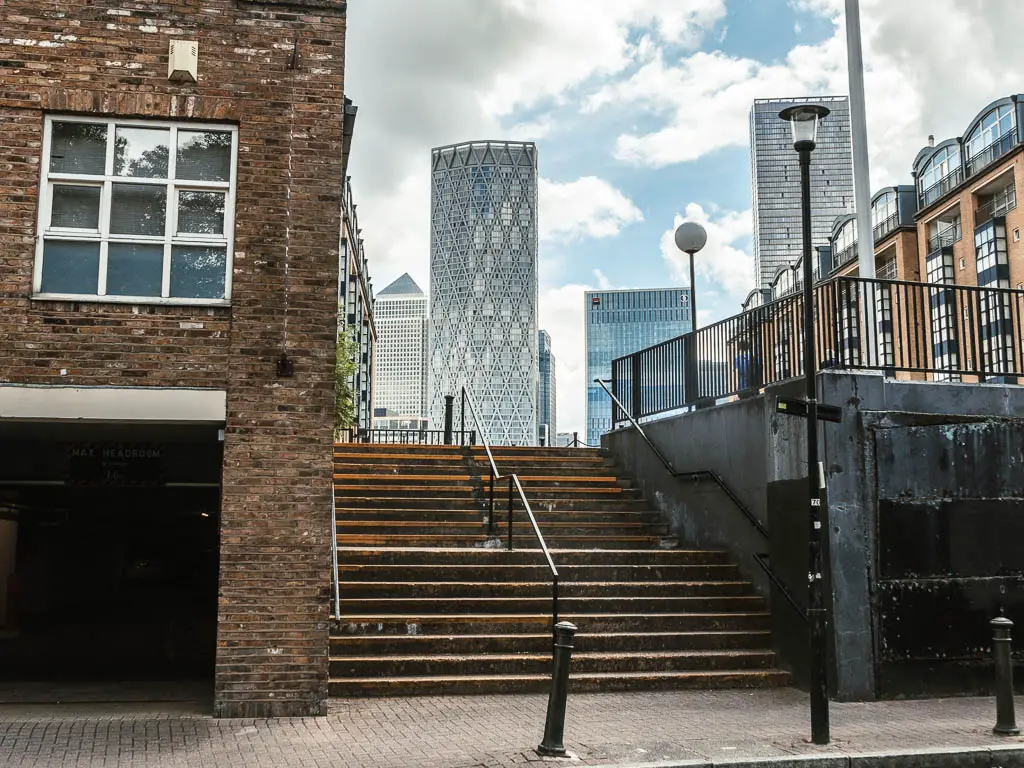 Steps leading up next to a brick building, with tall skyscrapers ahead.