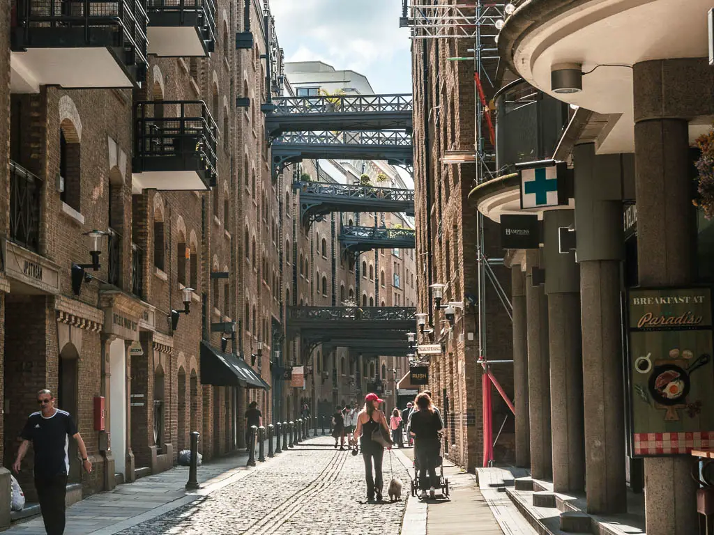 A pedestrian walkway between the tall buildings with bridges between them, and lots of people walking below.