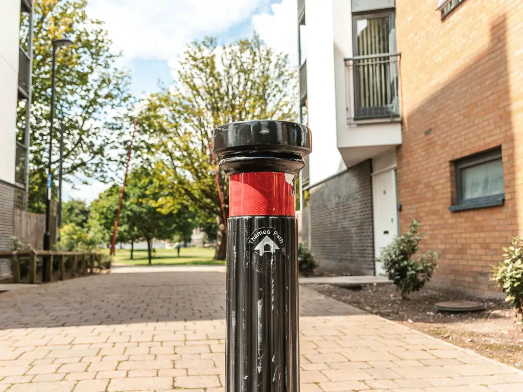 A thames path sign on a black post, pointing ahead.