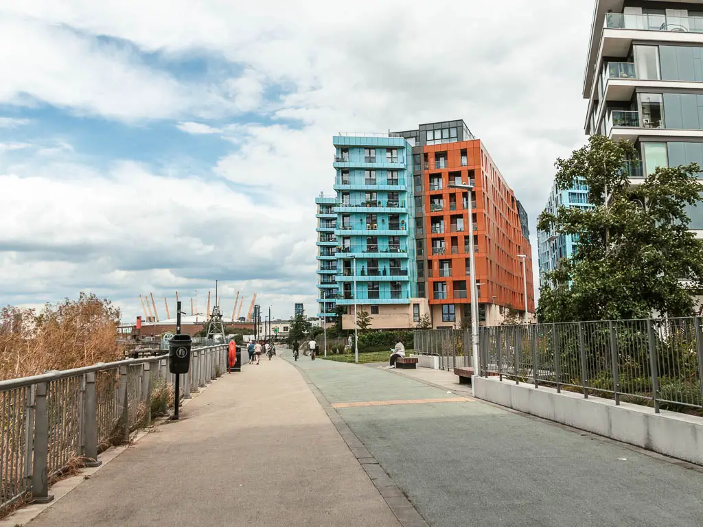 A wide walkway with orange and light blue coloured apartment building ahead. 