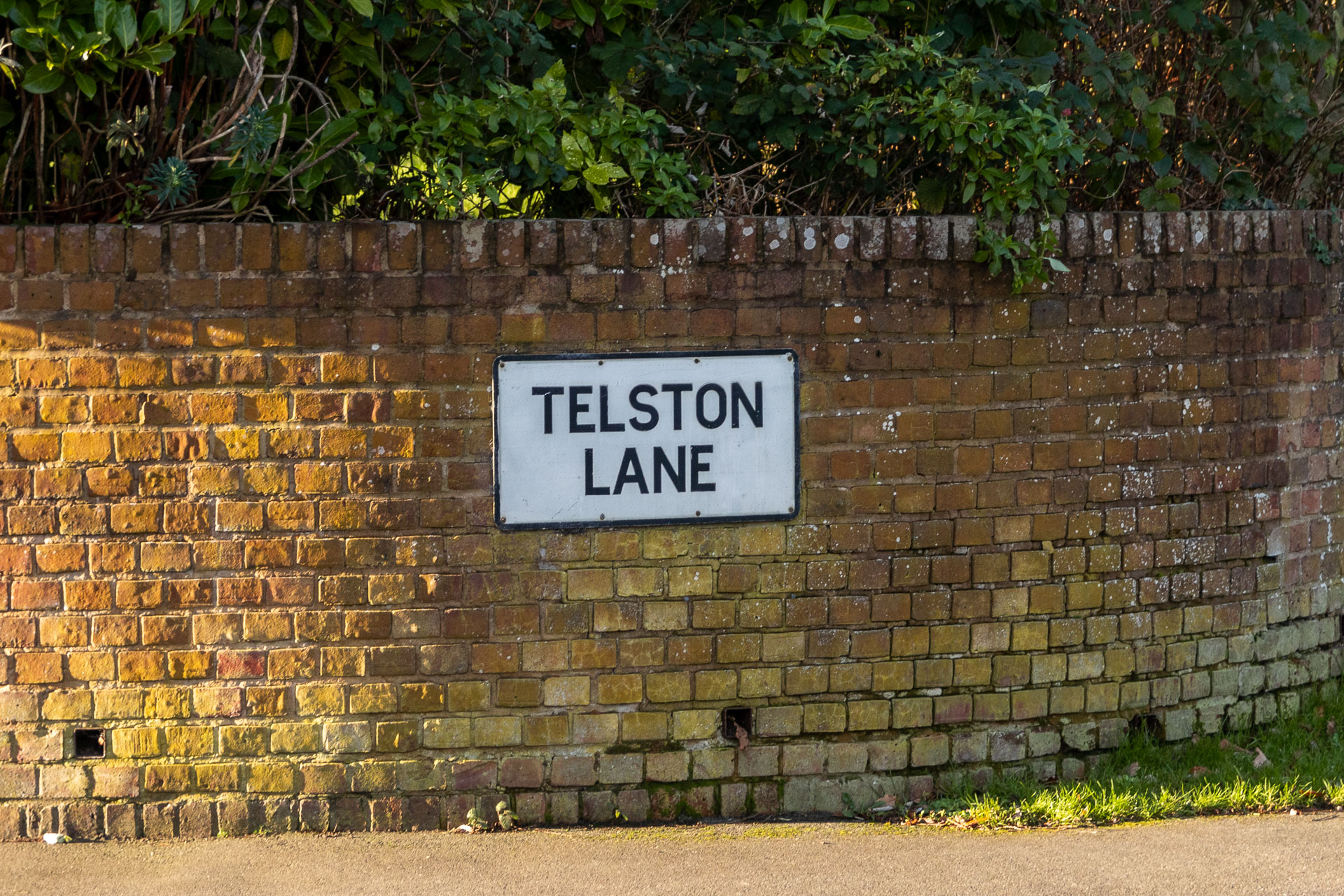 A brick wall with a road sign saying 'Telston Lane' on it.