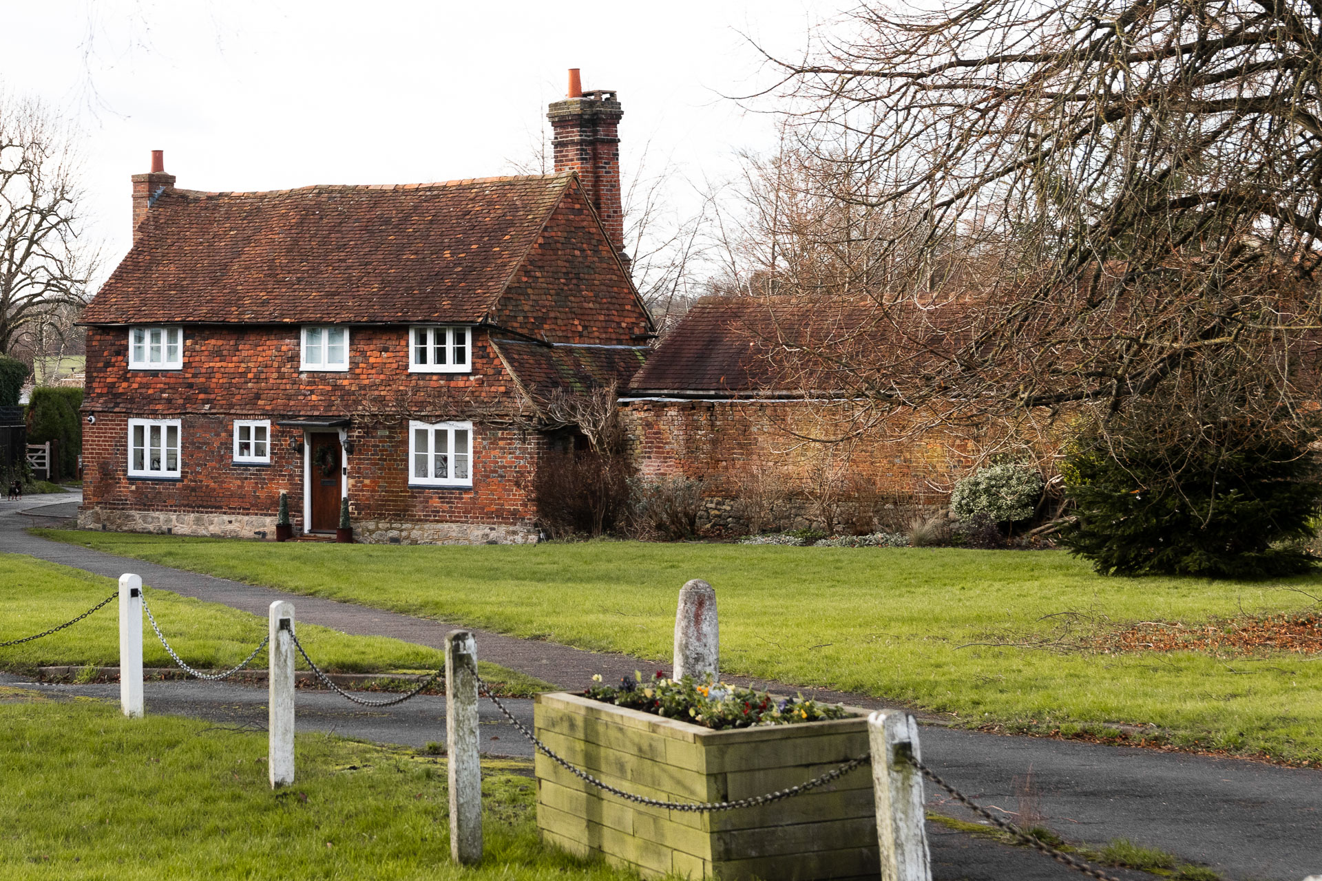 A neatly cut green with a path running through it, leading to an old cottage ahead.