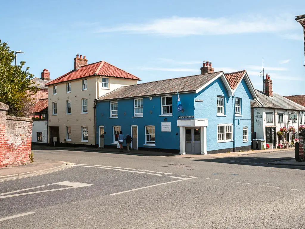 A road junction in Aldeburgh, with pastel blue and cream houses on the other side of the road.