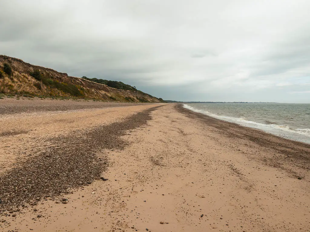 Looking along the long sandy beach with cliffs to the left and sea to the right, on the walk from Snape to Dunwich.