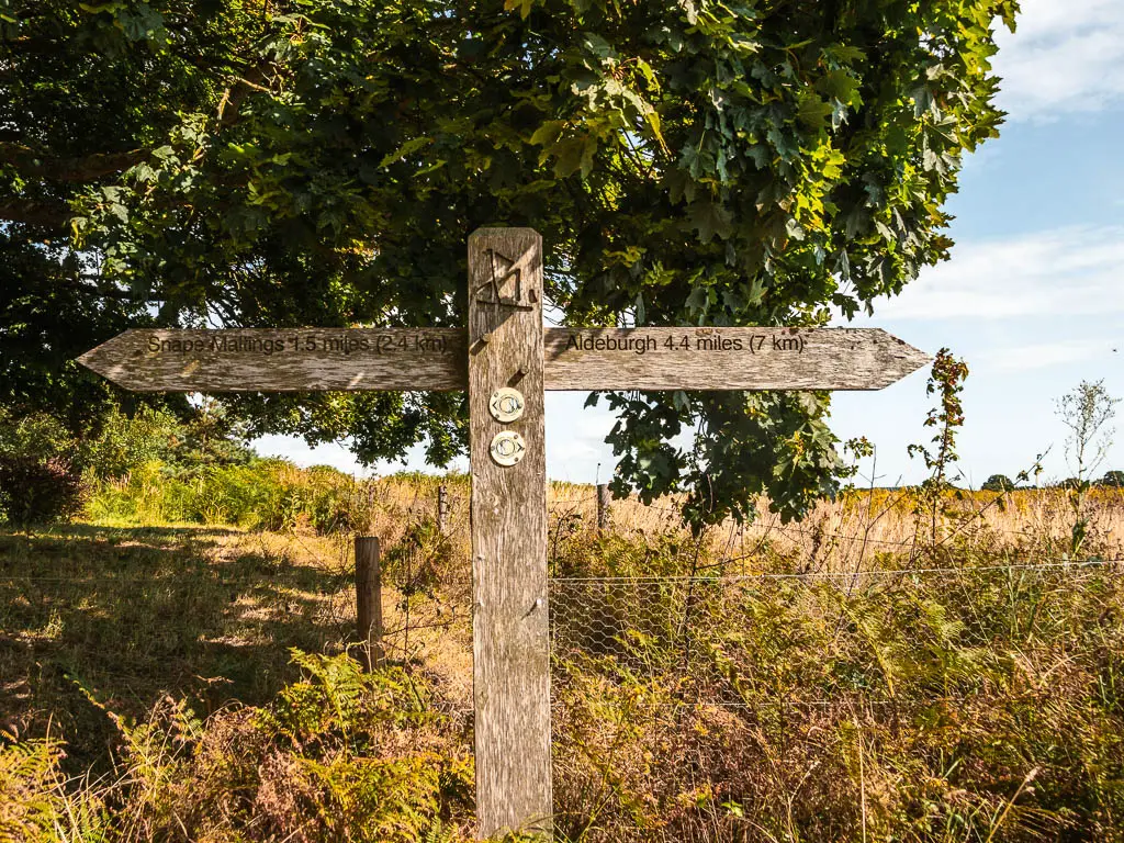 A wooden trail sign pointing right for Aldeburgh, and left for Snape. 