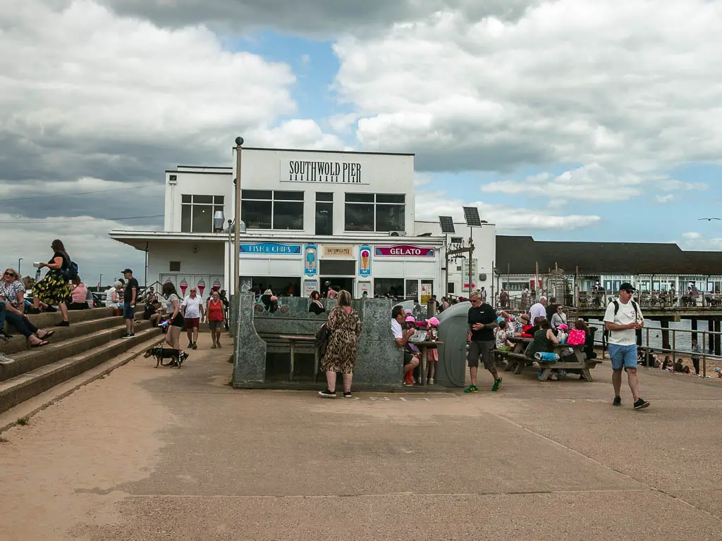 The southwold pier building with masses of people walking about.