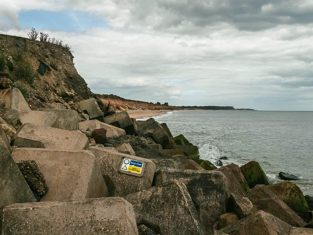 A mass of stone blocks, with the sea too the right, and a beach on the other side.