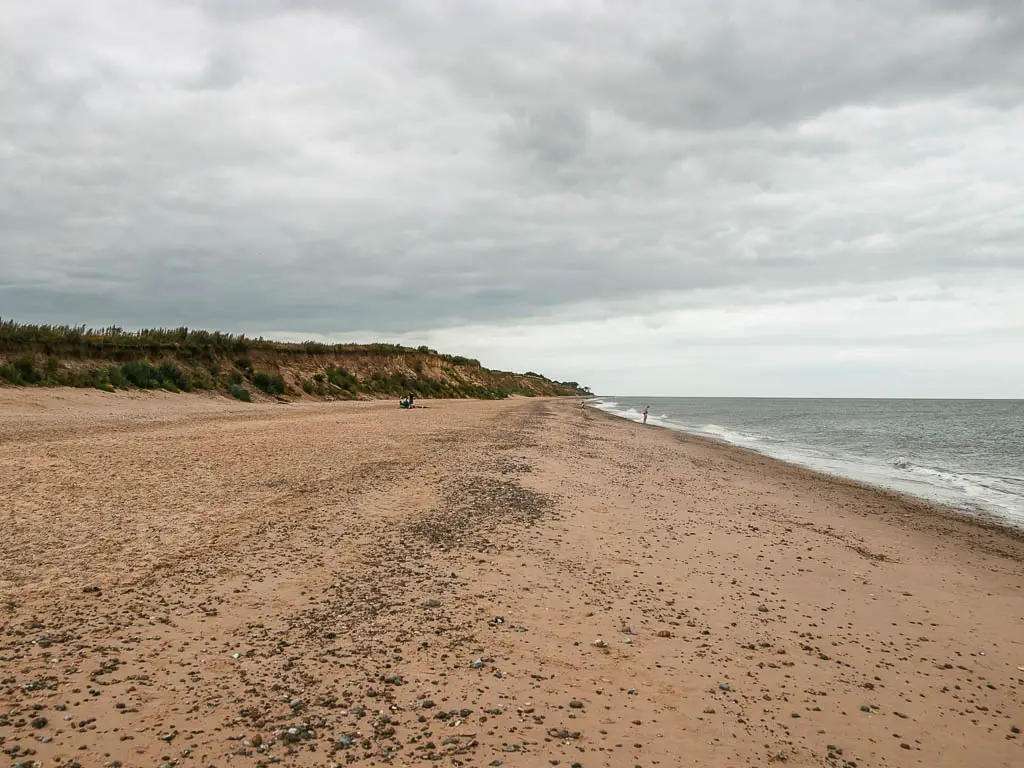 A long straight sandy beach on the walk from Dunwich to Kessingland. There are cliffs ahead to the left, and the sea to the right.